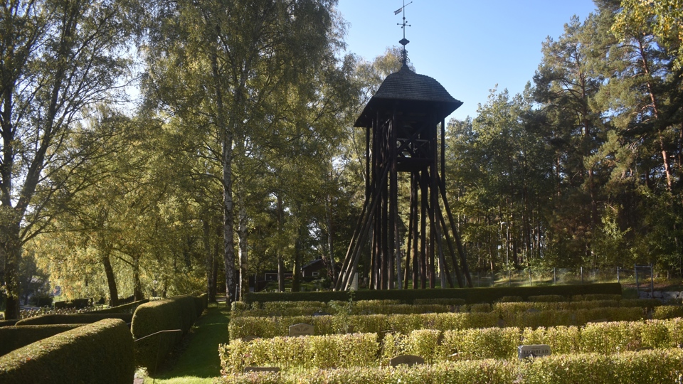 En klockstapel i trä på en begravningsplats.