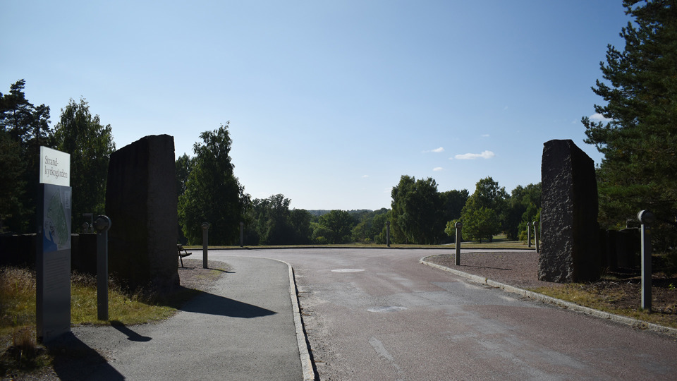 En entré för gående och bilar med väldigt stora stenar på vardera sida om entrén.