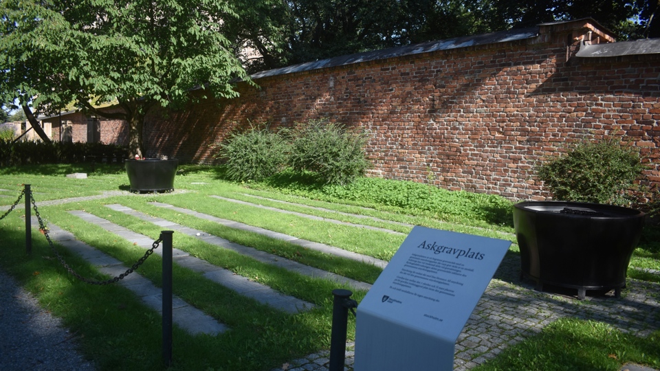 En inhängnad askgravplats med inskriptioner över gravsatta.