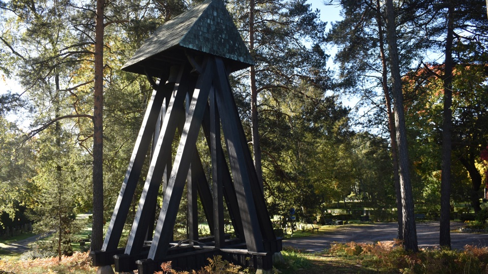 En klockstapel av trä i en dunge med tallar.