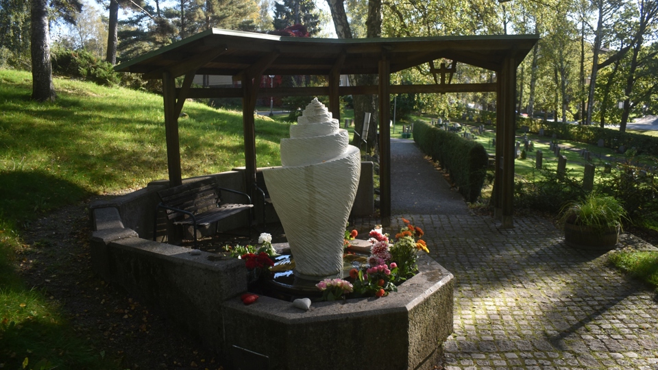 En skulptur med blommor runt i en minneslund.