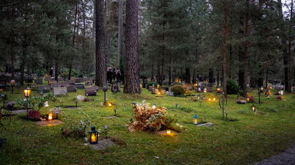 Gravar med tända gravljus på en begravningsplats.