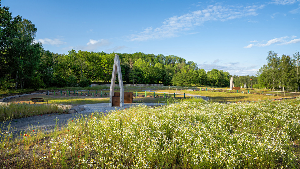 En begravningsplats med öppna fält och ängsblommor blandat med gravmonument.